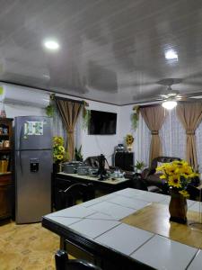 Una cocina y una sala de estar con refrigerador y una mesa. en Casa Sunflower, en Puerto Jiménez