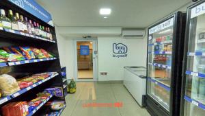 Apartamento em Bauru em Frente ao Aeroporto في Bauru: ممر متجر بقالة مع لافتة متجر +صورتان