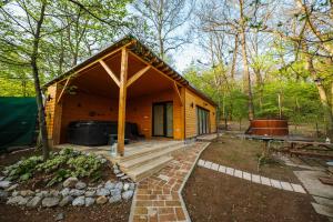 a small wooden cabin in the woods with a patio at Zegzug Noszvaj in Noszvaj