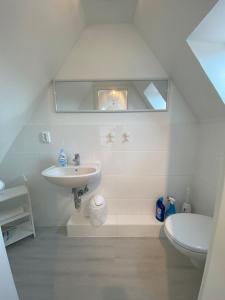 a white bathroom with a sink and a toilet at Ferienhaus Parkblick in Travemünde
