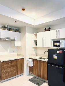 a kitchen with white cabinets and a black refrigerator at 2br Unit in Matina Enclaves Davao in Davao City