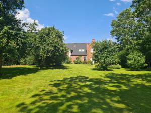 a house with a large yard with green grass and trees at Druidenhain Hof Neudamm in Neukirchen