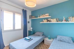 two beds in a room with blue walls and a window at Mon nid d'aigle in Olmeto