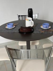 a black table with two cups and a plate of food at Buriti Home in Lucas do Rio Verde +12 photos