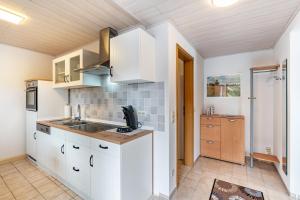 フォルバックにあるFerienwohnung Brigitteの白いキャビネットとシンクのあるキッチン