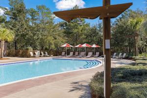 a pool with chairs and umbrellas in a resort at Redfish Village M2-329 in Blue Mountain Beach