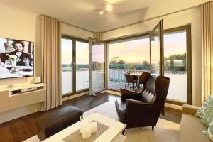 un salon avec une télévision, une table et des chaises dans l'établissement Villa Deichgraf Meerblick, à Börgerende-Rethwisch