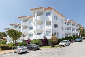 a white apartment building with cars parked in a parking lot at Lovely 2 bed apt overlooking golf in Mijas Costa