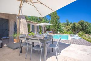 una mesa y sillas con una sombrilla y una piscina en Villa La Louisière - Les Issambres, en Saint-Peïre-sur-Mer