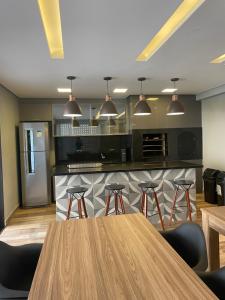 a kitchen with a wooden table and bar with stools at Batel Guest House-Suite Queen Quarto 1 in Curitiba