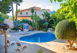 a swimming pool in a yard with chairs and a house at Verano in Calpe