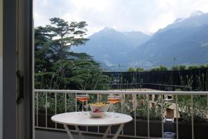 a table on a balcony with a view of mountains at Nuvola 5th Floor in Merano