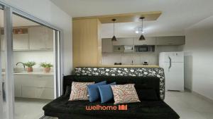a living room with a couch with pillows and a kitchen at Apartamento em Bauru com Vista para Montanha in Bauru