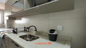 a kitchen counter with a sink and a trash can at Apartamento em Bauru com Vista para Montanha in Bauru
