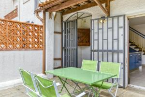 une table et des chaises vertes sur la terrasse dans l'établissement Apartamento Roses Victor, à Roses