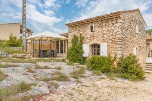 an old stone house with a tent in front of it at Les Buisses - Petit Gite in Simiane-la-Rotonde