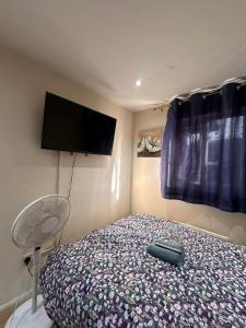 a bedroom with a bed with a tv on the wall at BUDGET Small Rooms in Thamesmead