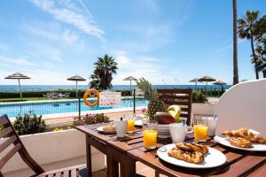 una mesa con comida y vistas a la piscina en Seafront Beach house Rocas del Mar, en Mijas