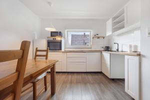 a kitchen with white cabinets and a wooden table at Haus am Garten in Brunkensen +15 photos