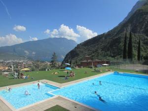 une grande piscine avec des gens dans un champ et des montagnes dans l'établissement Casa Sara with swimming pool, à Riva del Garda