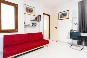 a red couch in a living room with a television at Bellarosa alloggio Stella Marina in Quartu SantʼElena