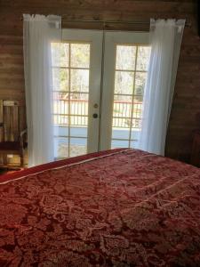 a bedroom with a red bed and two windows at Meadow Creek Cabin in Camino +16 photos