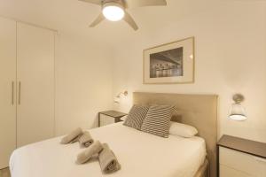 een witte slaapkamer met 2 bedden en een plafondventilator bij Apartamento Yumbo Maspalomas in Maspalomas +16 foto's