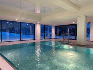 an indoor swimming pool in a building with windows at Fewo Lieblingsplatz mit Indoor Pool in Schluchsee