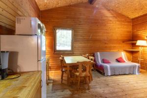 ein Zimmer mit einem Tisch, einem Bett und einem Kühlschrank in der Unterkunft Chalet Orange - Piscine Partagée in Darbres