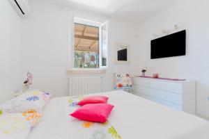 a white bedroom with a bed with red pillows at Deliziosa Villa Patrizia a Otranto in Otranto