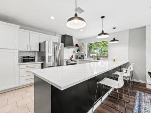 a kitchen with white cabinets and a large island with stools at 4brping Pong2500 Sq Ft in Bedford