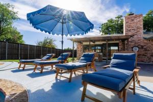 a group of chairs and an umbrella on a patio at Palm Springs Pool & Game Room! in The Colony