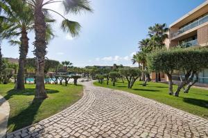 un chemin pavé dans un parc planté de palmiers dans l'établissement Apartamento Salgados Sol e Sal, à Guia
