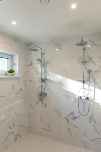 a bathroom with a shower with white marble walls at The Peaceful Vacation in Muratsi