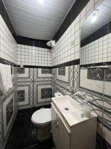 ein schwarz-weißes Badezimmer mit Toilette und Waschbecken in der Unterkunft Casa térreo in São José dos Pinhais + 2 Fotos