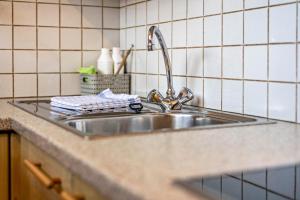 a stainless steel sink in a kitchen with white tiles at Haus zur Vogelweide App 2 in Dobbiaco +11 photos