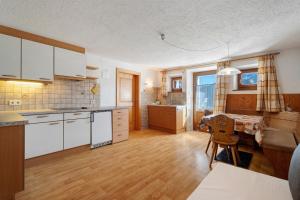 a kitchen with white cabinets and a table in it at Wegscheiderhof in Dobbiaco