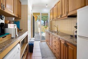 a kitchen with wooden cabinets and a white refrigerator at Casa de férias a 75 metros da praia in Campo de Baixo