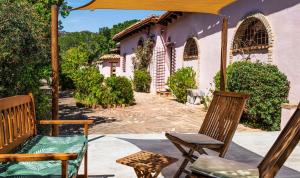 a patio with two chairs and an umbrella at Villa Fiori 3 in Is Molas 