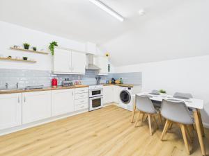 a kitchen with white cabinets and a table and chairs at Kings Corner in Warrenpoint