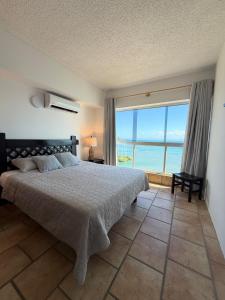 a bedroom with a bed with a view of the ocean at Mar & Relax, apartamento en primera linea de playa in Porlamar