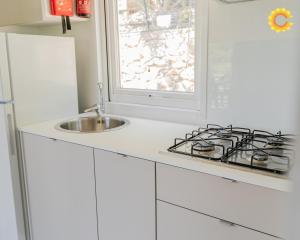 a white kitchen with a stove and a sink at Mobile Home Charme 176 in Pietra Ligure