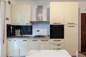 una cucina con armadi bianchi, tavolo e elettrodomestici neri di Residence Caravel 25 a Lido di Camaiore