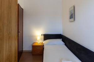 una camera da letto con un letto e un comodino con una lampada di Residence Caravel 25 a Lido di Camaiore