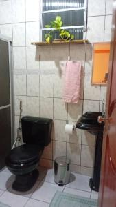 a bathroom with a black toilet and a sink at Quarto para COP30 in Ananindeua