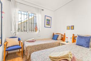 a room with two beds and a chair and a window at Seaside House in El Mojon in Pilar de la Horadada
