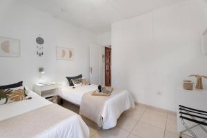 two beds in a room with white walls at Serene Terrace And Pool in Playa de las Americas +20 photos