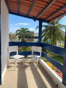 two chairs on a balcony with palm trees at Sol Mar Hostel in Santo Agostinho