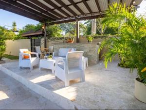 d'une terrasse avec des tables et des chaises blanches et un mur en briques. dans l'établissement Stylish 1r-1b Apt Near The Beach And Main Street, à Sosúa