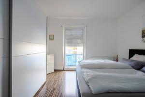 a white bedroom with two beds and a window at Fewo Konstanz City im Paradies in Konstanz